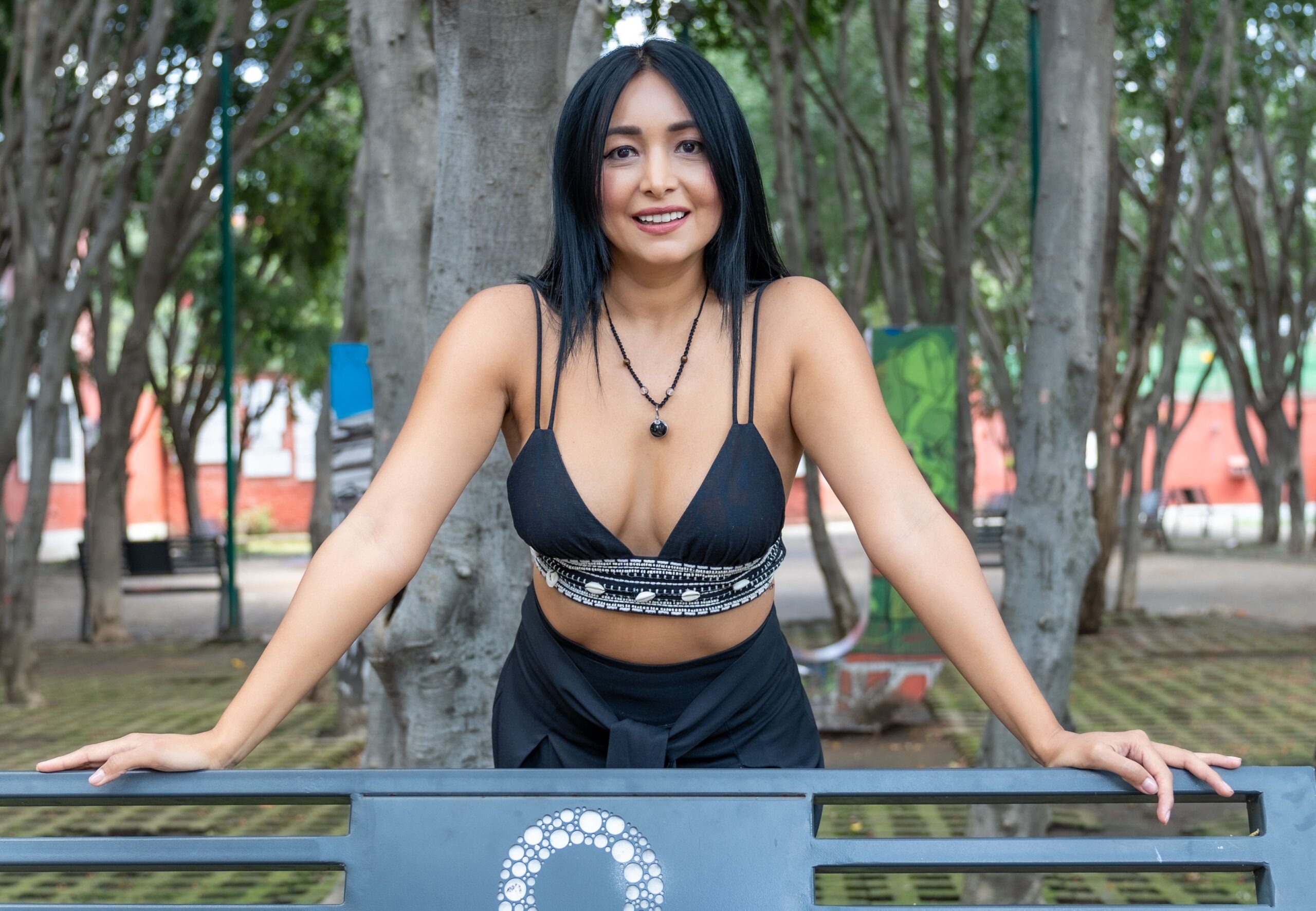 Smiling woman in a park bench at Ciudad de México, showcasing casual fashion.